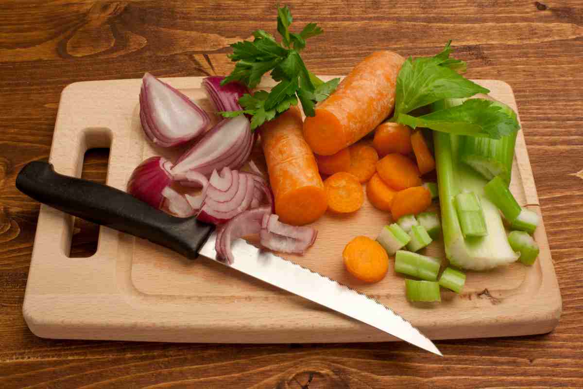 Degli ortaggi affettati su un tagliere con un coltello