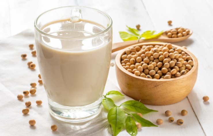 bicchiere di latte di soia e accanto dei fagioli di soia