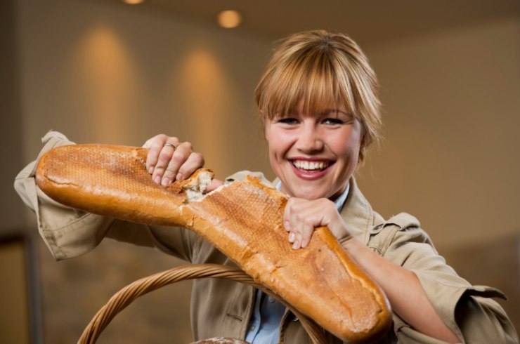 donna che sorride mentre spezza una baguette