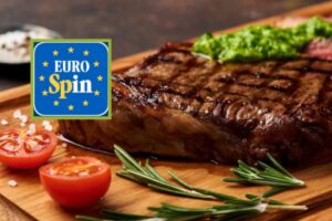 carne su un tagliere con accanto pomodori e rosmarino