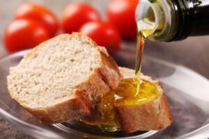 persona che versa un po' di olio sopra una fetta di pane