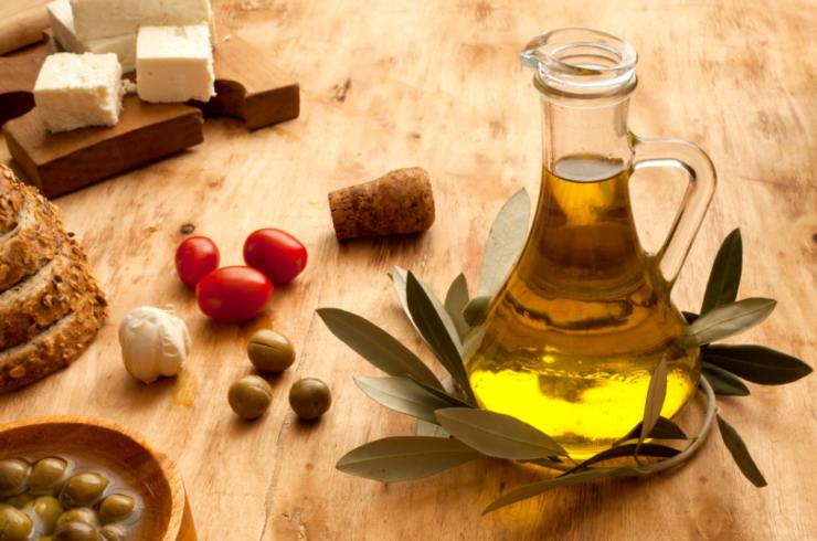 bottiglino di olio con accanto pomodori aglio e alloro