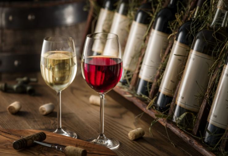 bottiglie di vino e due calici di vino, uno bianco e uno rosso