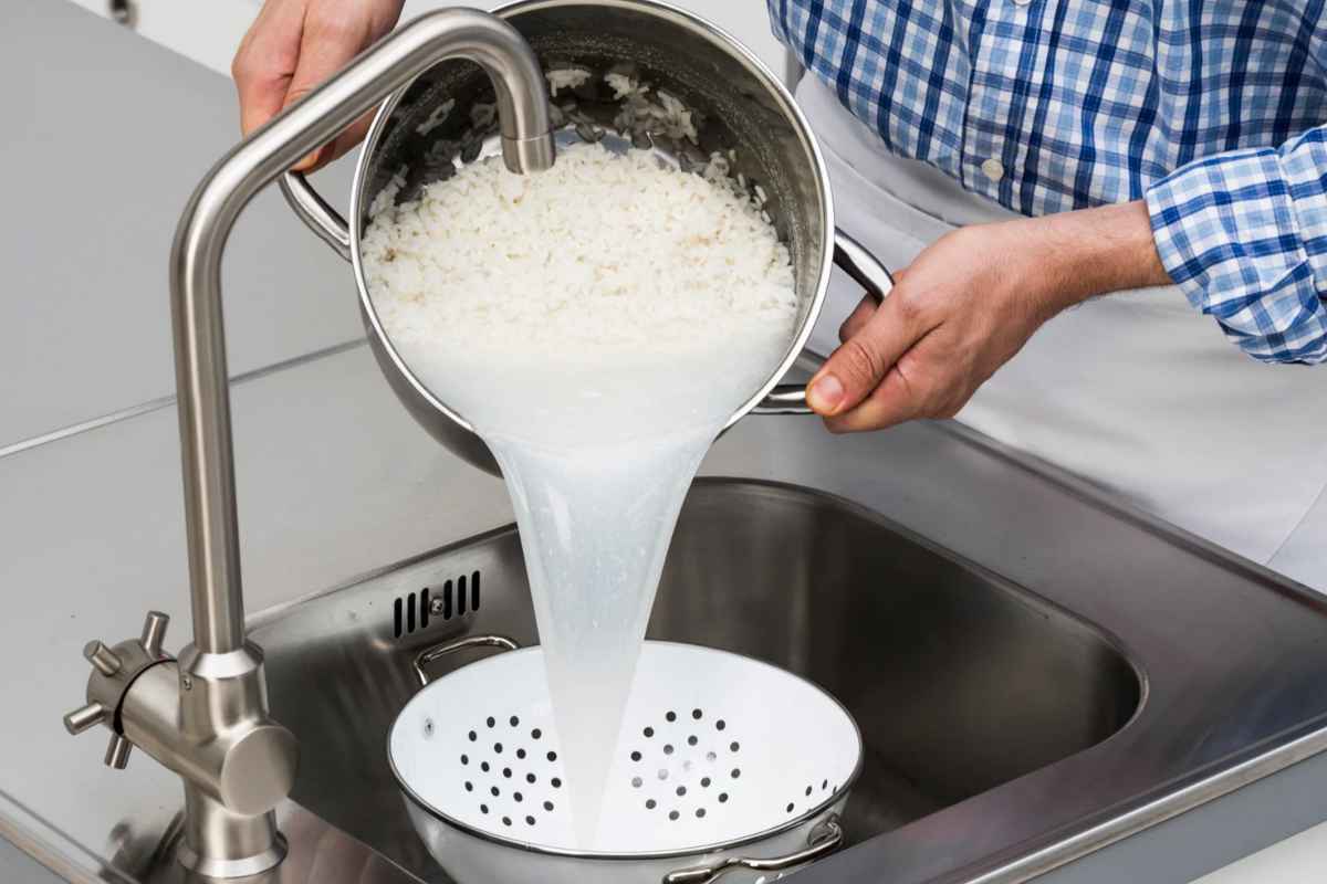 Persona che versa acqua di cottura del riso nel lavandino