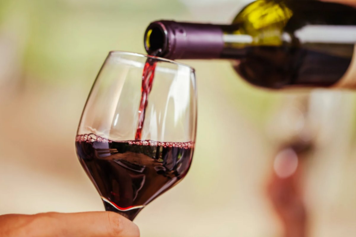 persona che versa del vino rosso in un calice