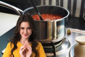Una pentola con il sugo ed una donna con espressione furba