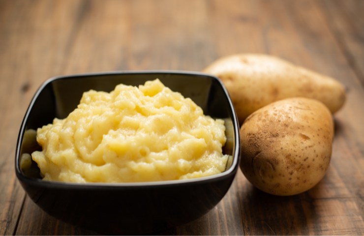 Purè di patate in una ciotola e due patate
