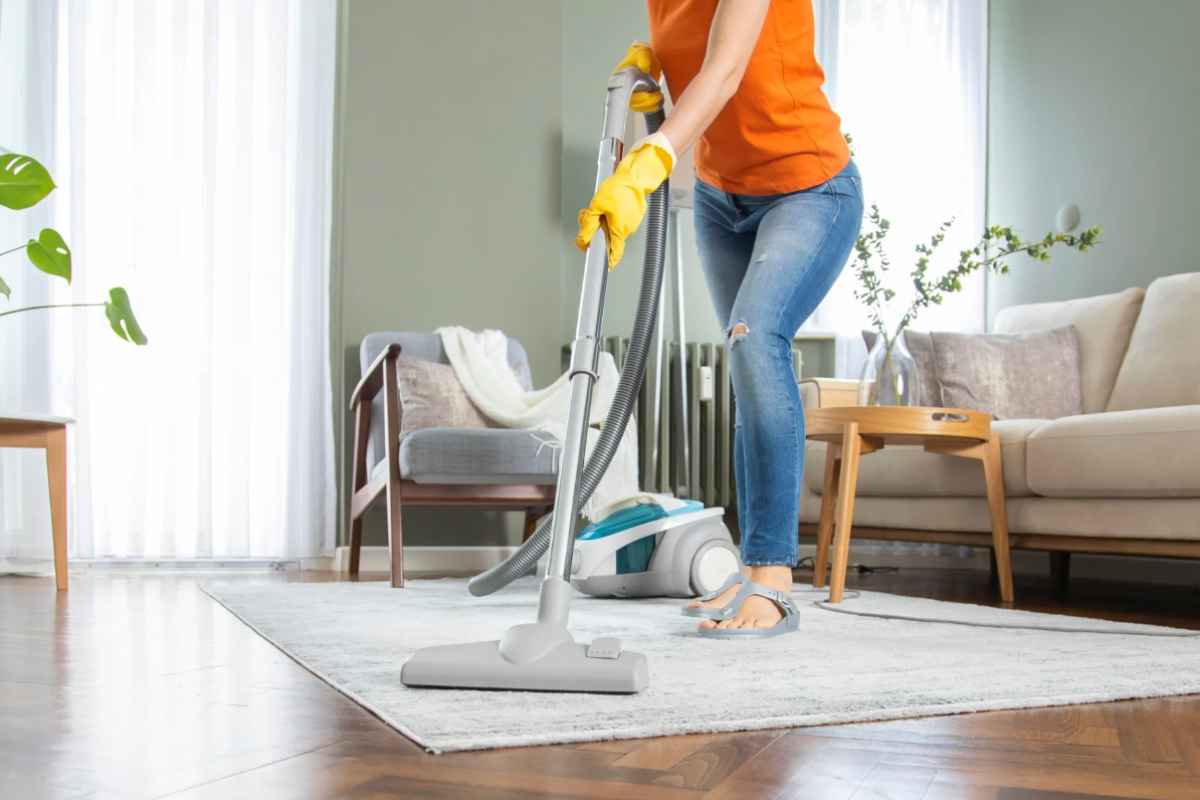 Donna che passa l'aspirapolvere sul tappeto