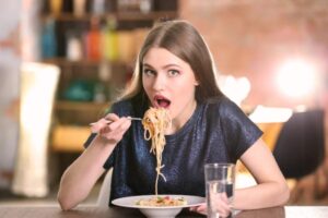 donna che mangia un piatto di spaghetti al sugo di pomodoro