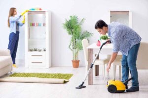 Due persone che puliscono stanza della casa