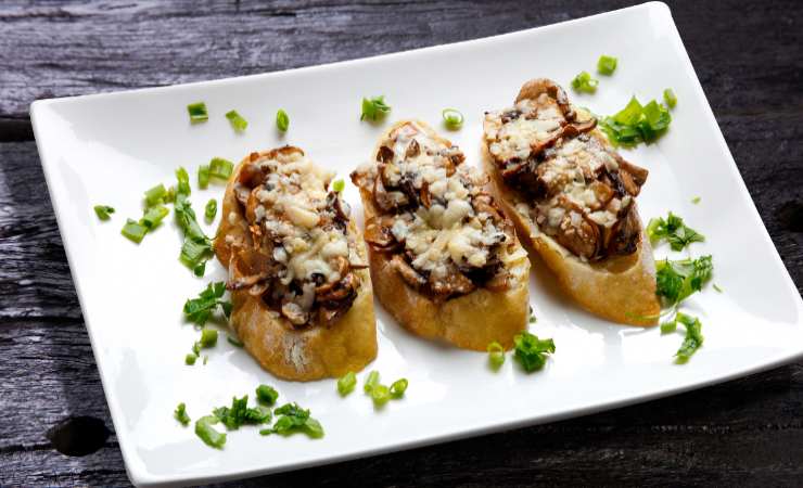 piatto di bruschette salsiccia funghi e formaggio