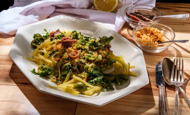 piatto di linguine alici capperi olive sul tavolo